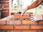 No Shortcuts For Bricklayers professional construction worker laying bricks and building barbecue in industrial site. Detail of hand adjusting bricks