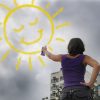 Gratitude, Optimism, and Investment Opportunities optimism and creativity: woman painting the sun onto the cloudy sky