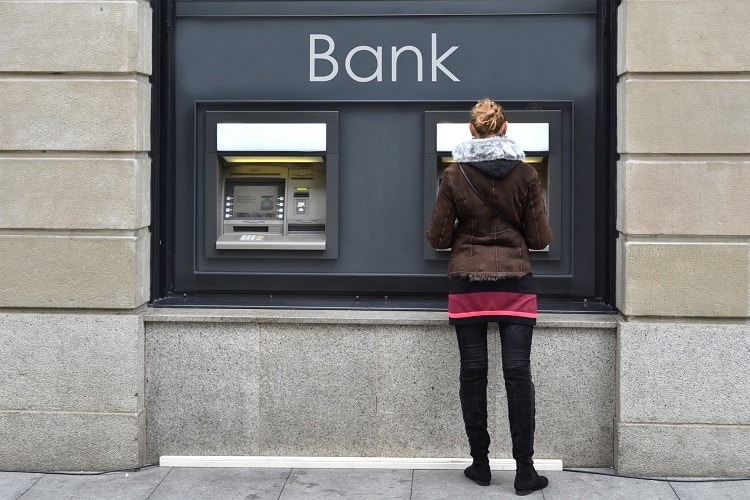 Woman at ATM. Retirees need reliable income for a secure retirement. Building a diversified portfolio of income-producing assets is one way to generate retirement income. 