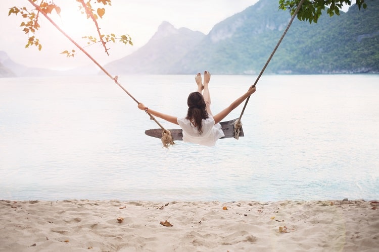 Women swinging freely at the beach. Calculate your financial independence number to determine when you have enough money to retire. 