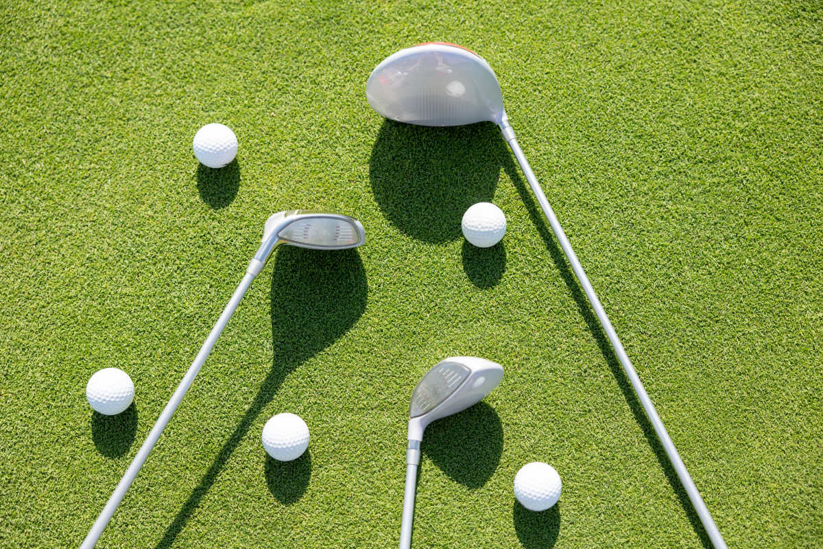 Three golf clubs and five golf balls. 